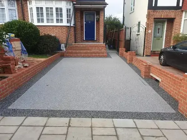 Newly completed resin-bound driveway with brick garden walls in front of a home.